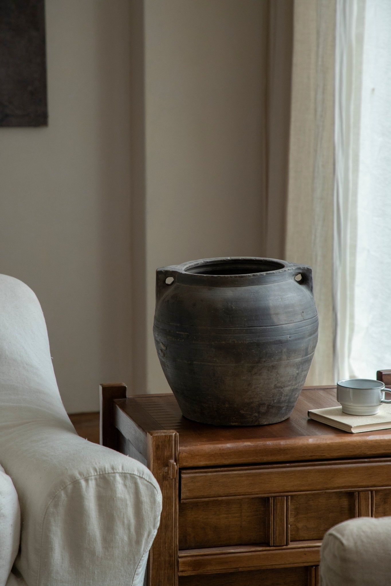 Large vintage clay pot with handles, on a wooden table, home decor accent, neutral colors, clay material.