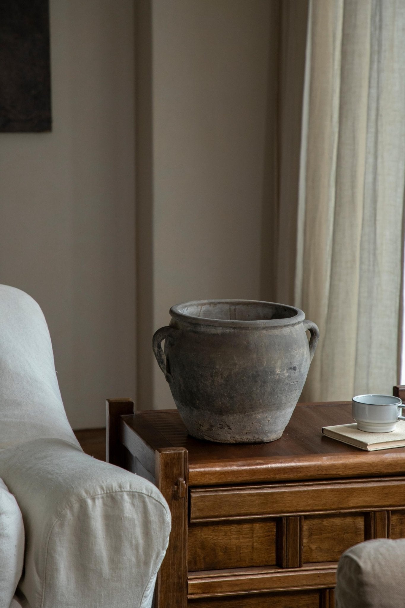 Vintage clay pot with handles, neutral home decor, on a wooden table, clay material.