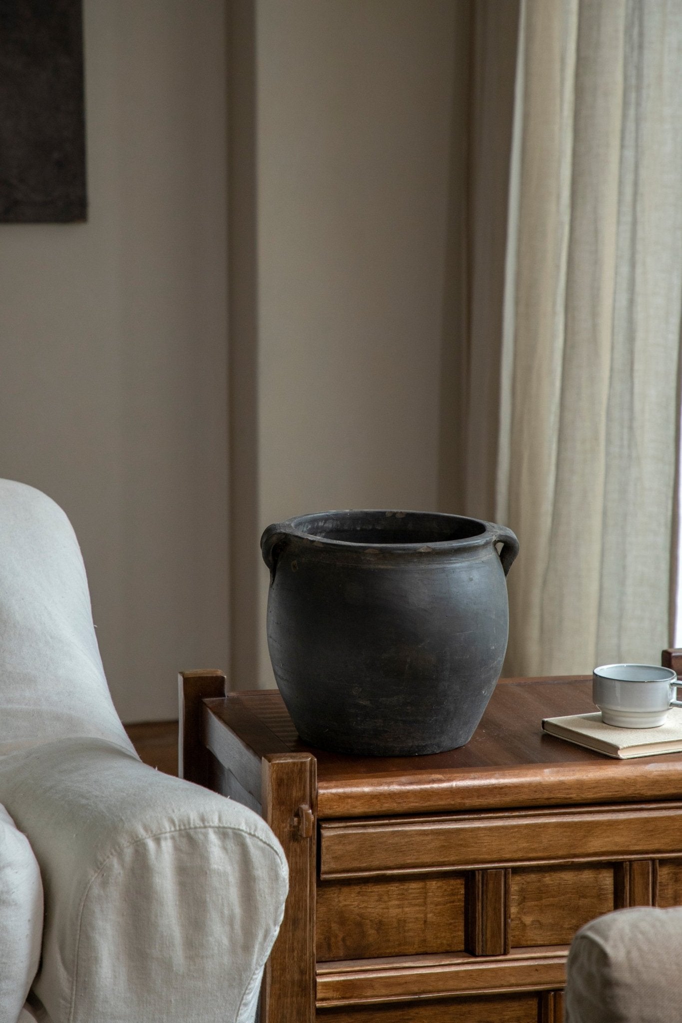 Large vintage clay pot, neutral home decor, on wooden table with teacup. Clay material.