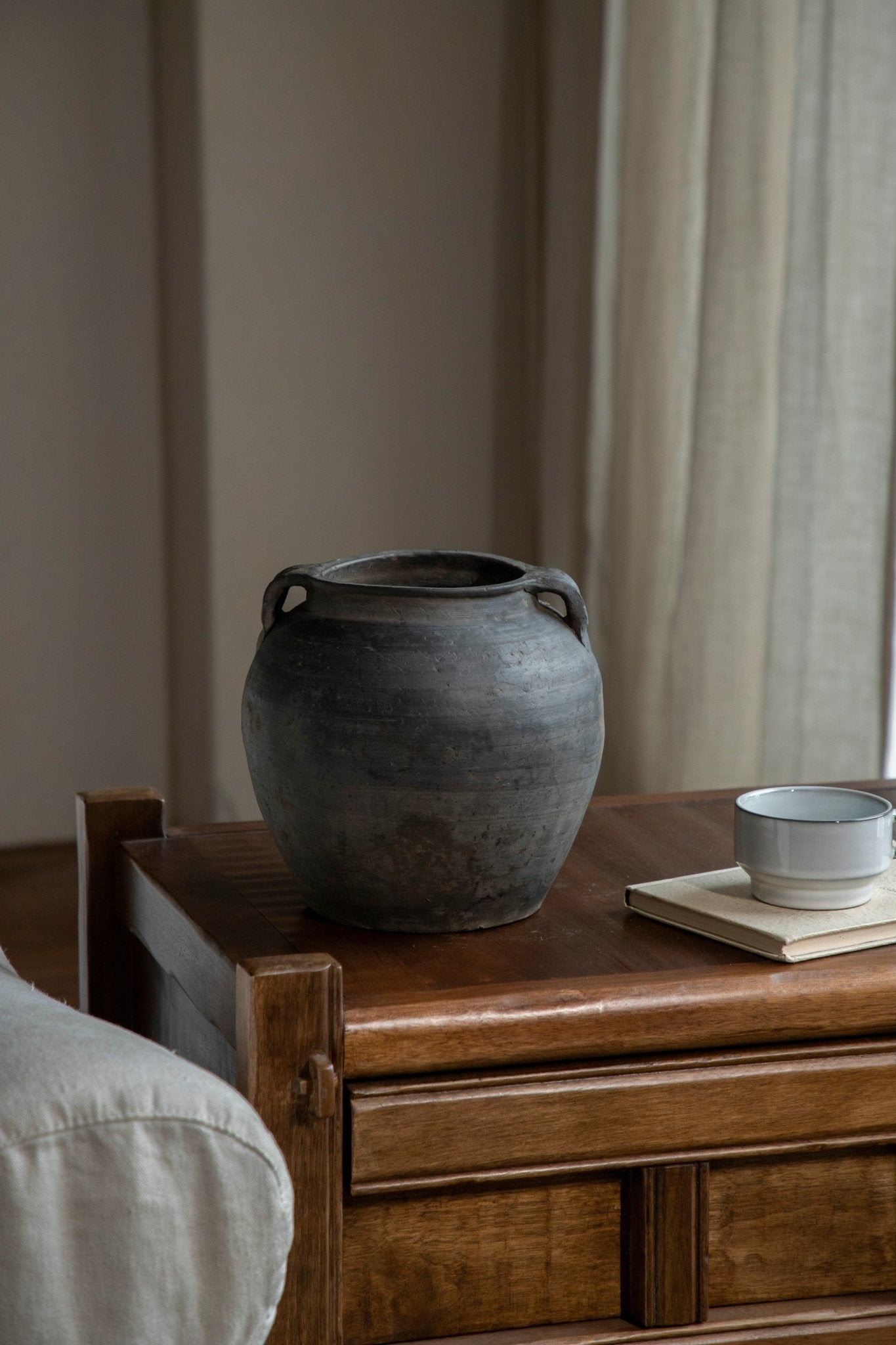 Vintage clay pot with handles, neutral home decor accent on wooden table with teacup