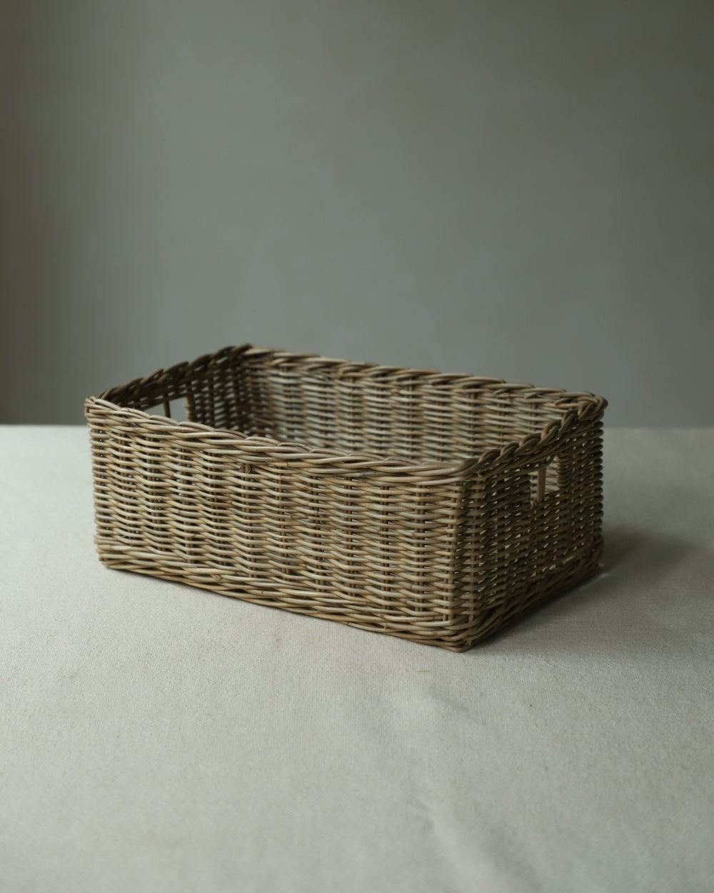 Etta storage basket: Hand-woven natural rattan with cut-out handles for tabletop organization.