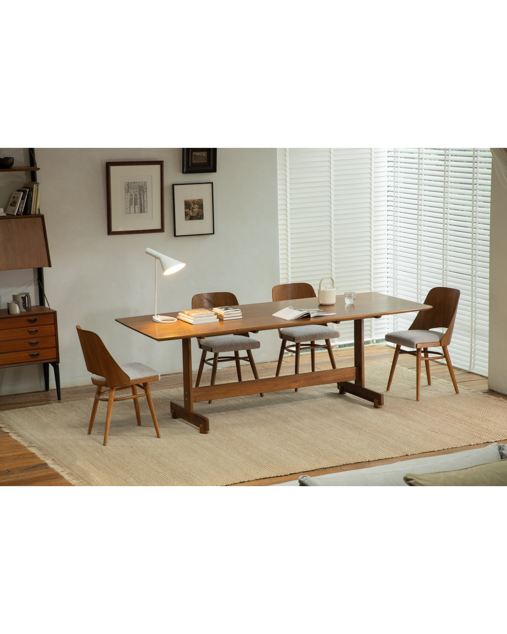 Mid-century modern Shell chairs with curved teak frames and grey upholstered seats around a wooden table.