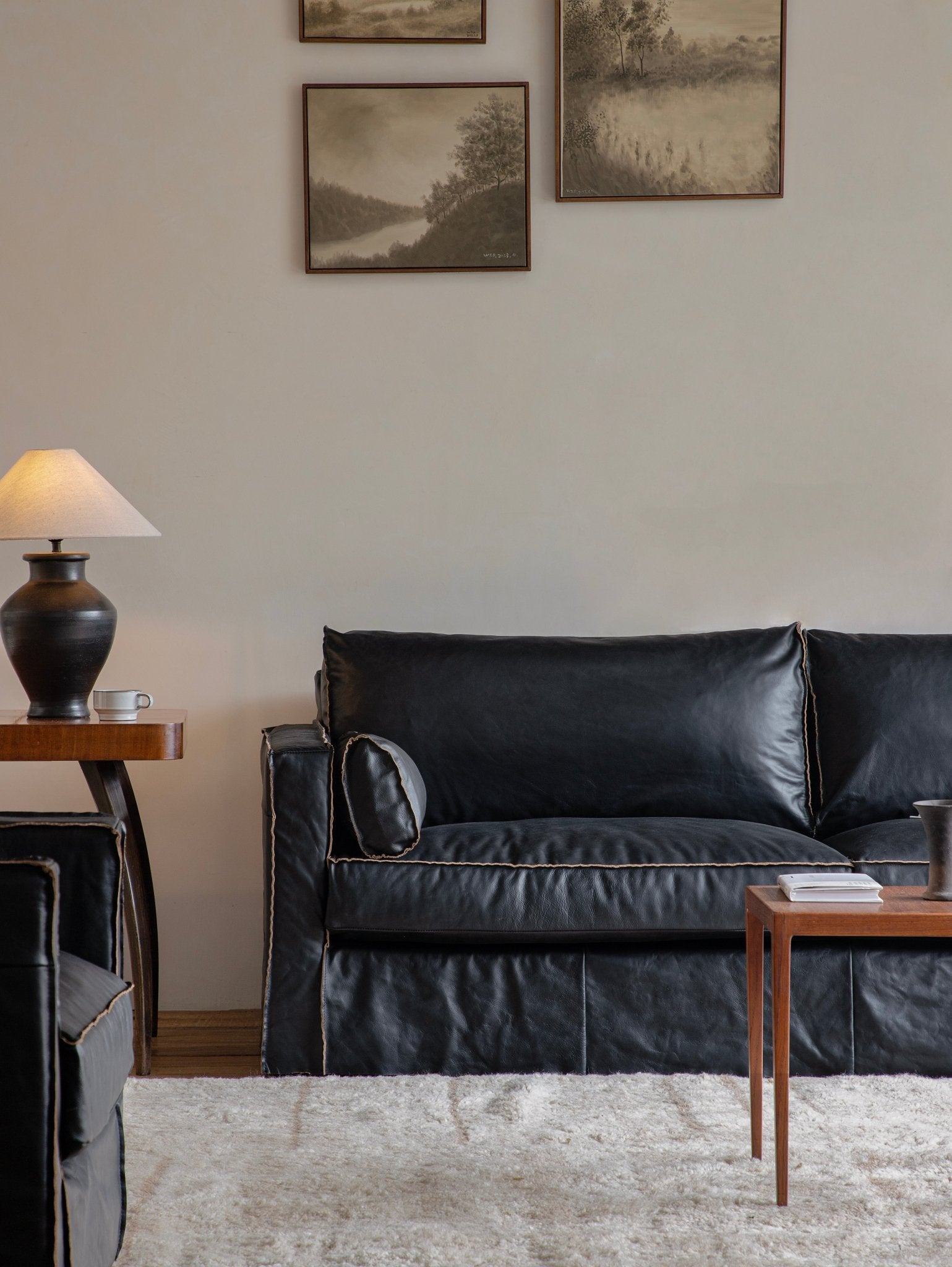 Black skirt leather sofa in a modern living room setting with artwork, highlighting top-grain leather skirt design