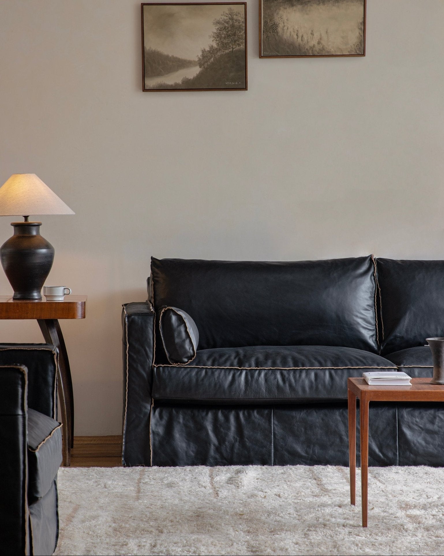 Black skirt leather sofa in a modern living room setting with artwork, highlighting top-grain leather skirt design