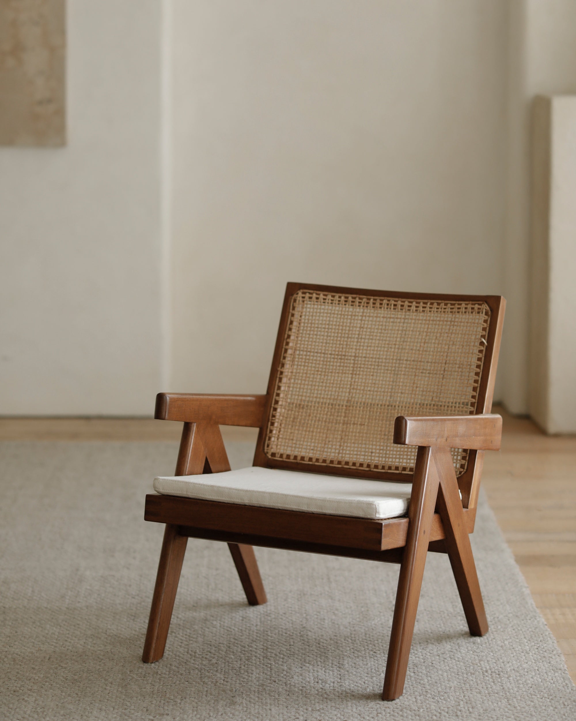 Chandigarh Armrest Easy Chair: Natural teak frame, woven rattan back, white cushion.