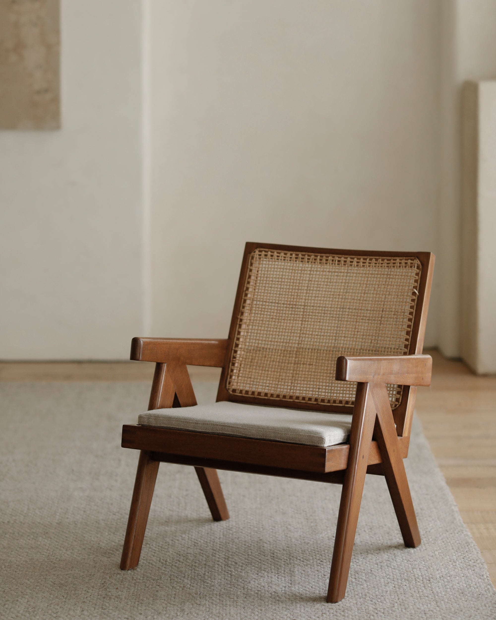 Natural teak Chandigarh Armrest Easy Chair with rattan weave back and seat, and light cushion.