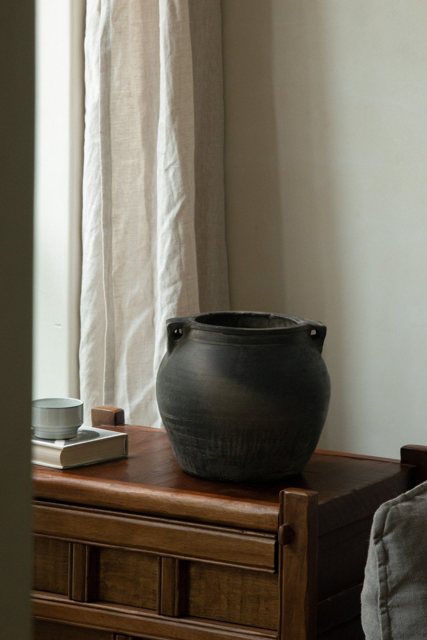 Vintage clay pot with handles, home decor accent, clay material on wooden table, neutral color.