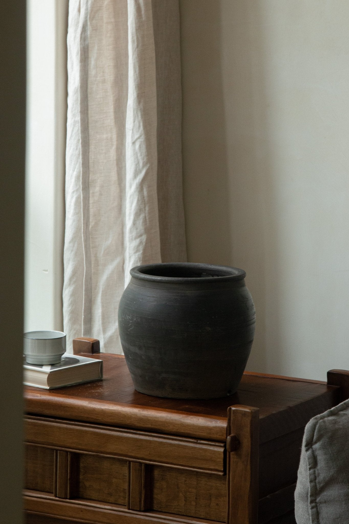 Large black clay pot, home decor accent, neutral color palette, vintage style on wooden chest