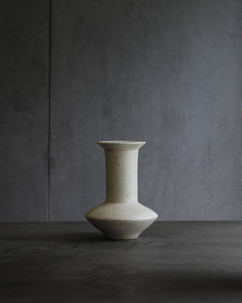 Off-white ceramic vase, minimalist design for home decor. Features a wide base, a narrow neck, and a flared rim.