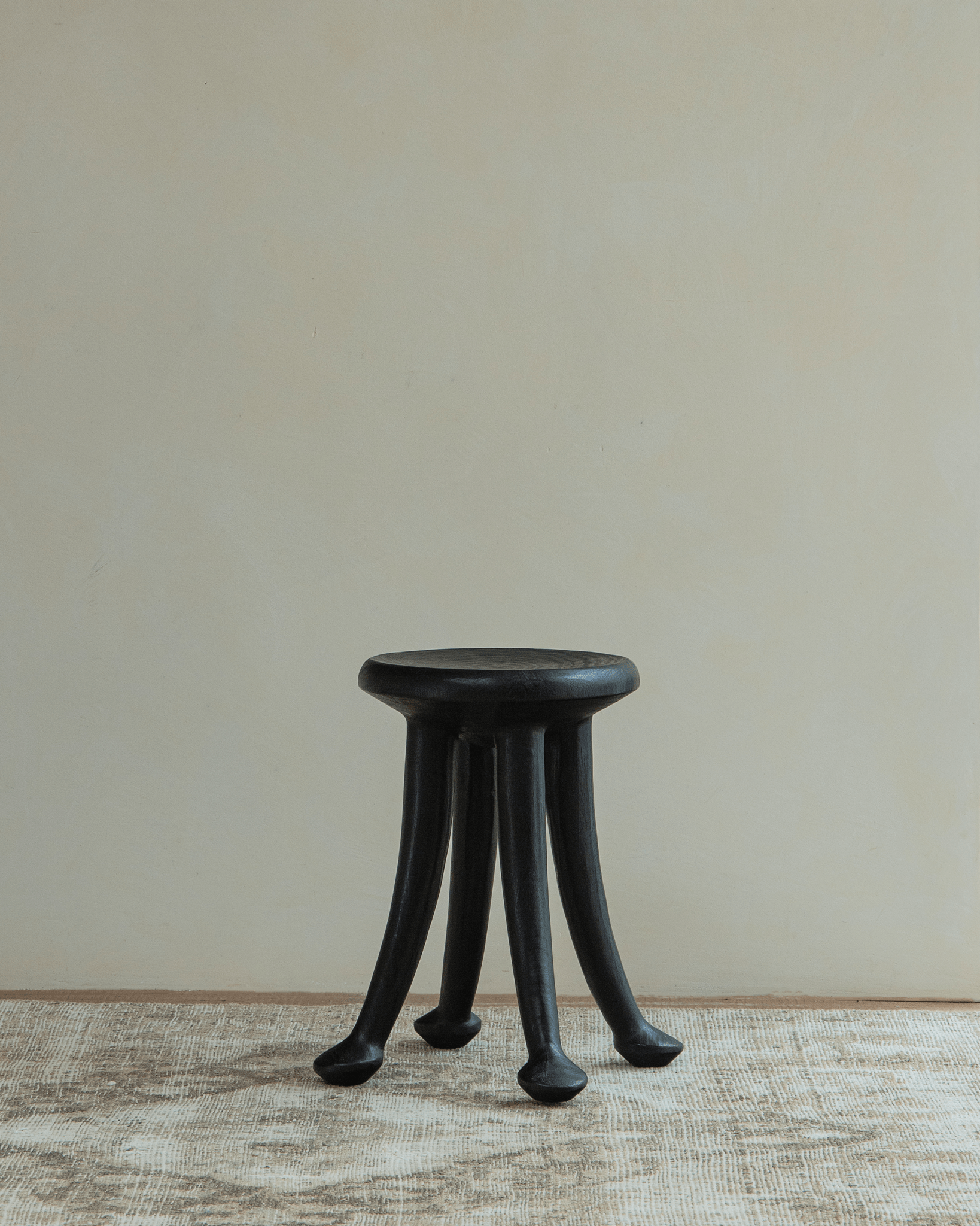 Black Sploot Stool, Samanea saman wood, modern three-legged design for living room decor.