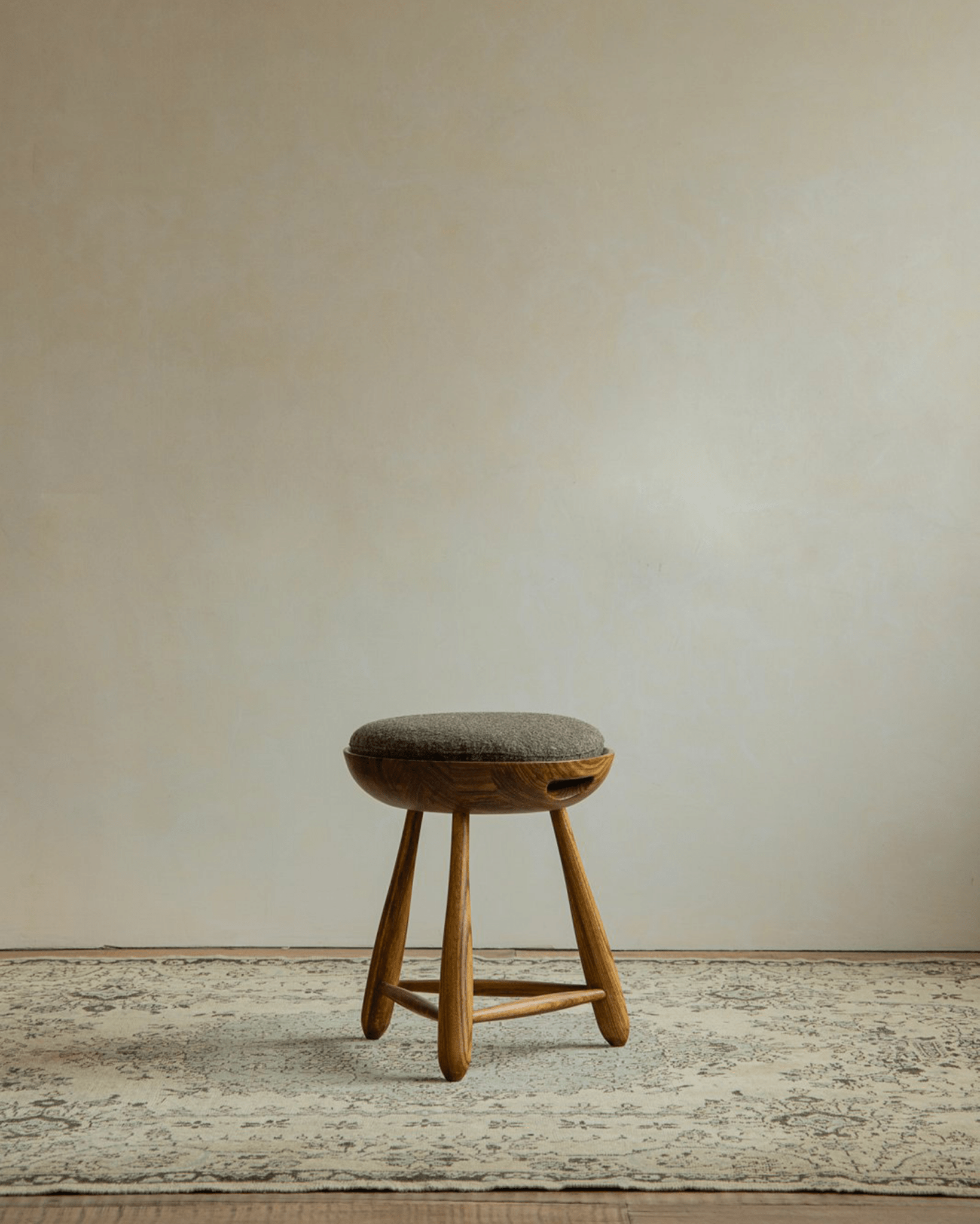 Zebrawood Mocho stool with gray upholstered seat, organic design, tripod legs. Modern design.