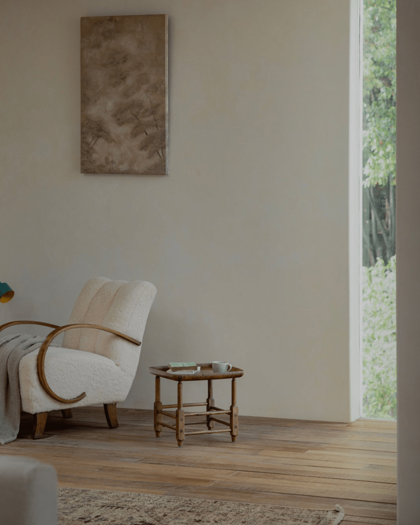 Cozy living room interior with sherpa armchair, wooden side table, natural light, and artwork on wall.
