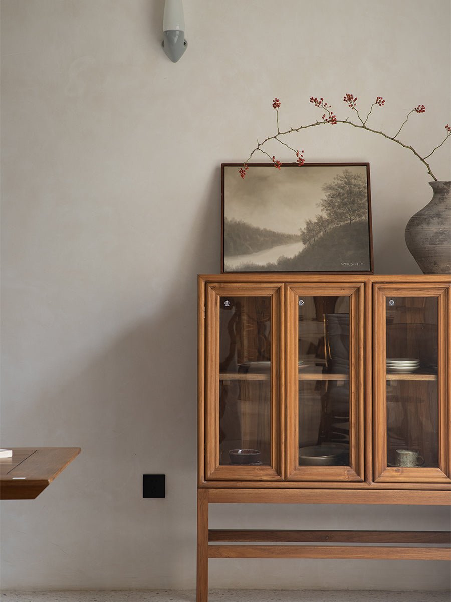 Teak wood Stilt Cabinet with glass doors, displaying tableware in a dining room setting; elegant storage solution.