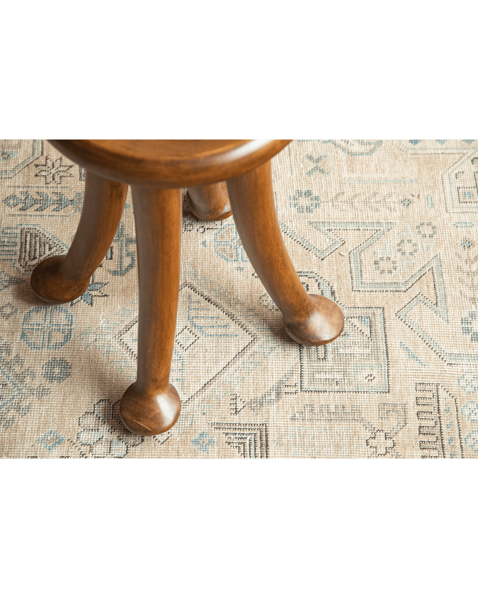 Sploot Stool wooden legs detail on patterned rug, natural Samanea saman finish