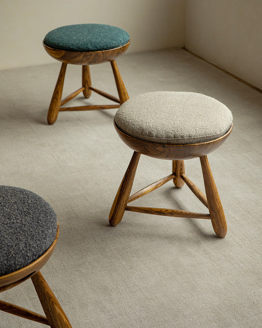 Mocho Stool in zebrawood with teal, light gray, and dark gray cushioned seats. Modern stool design.