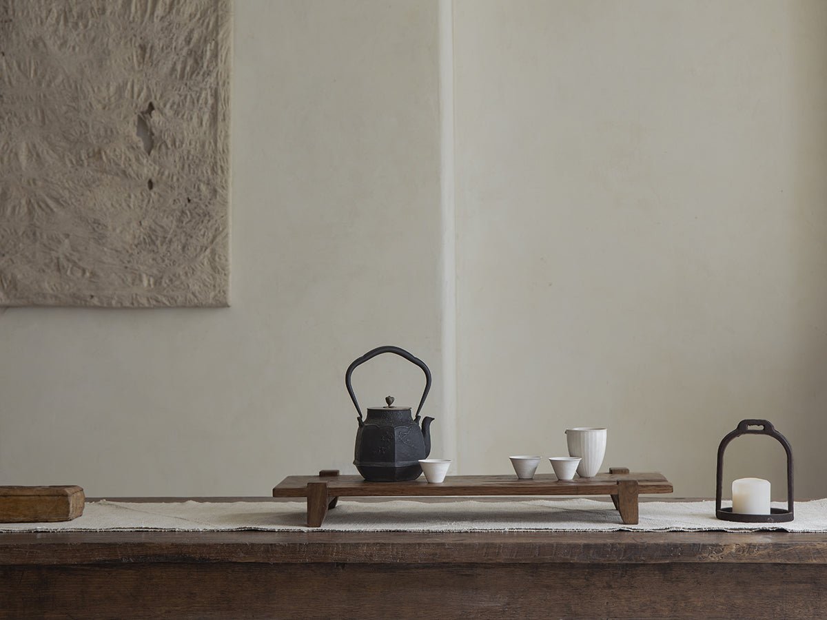 Chinese tea tray set with reclaimed wood tray, black teapot, and white cups, rustic and antique design.