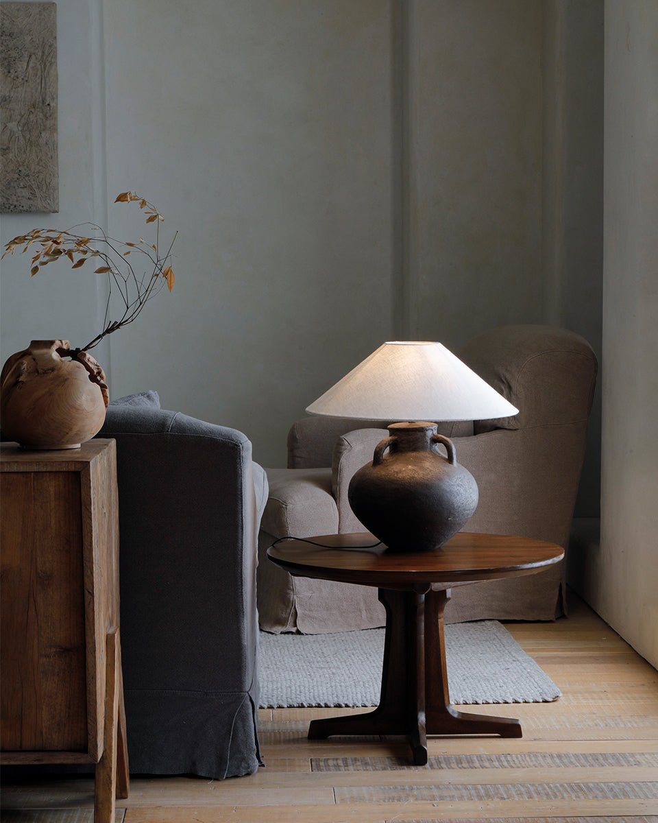 X Table in a room, featuring wooden table with X-shaped legs, side table with ceramic lamp, showcasing elegant design