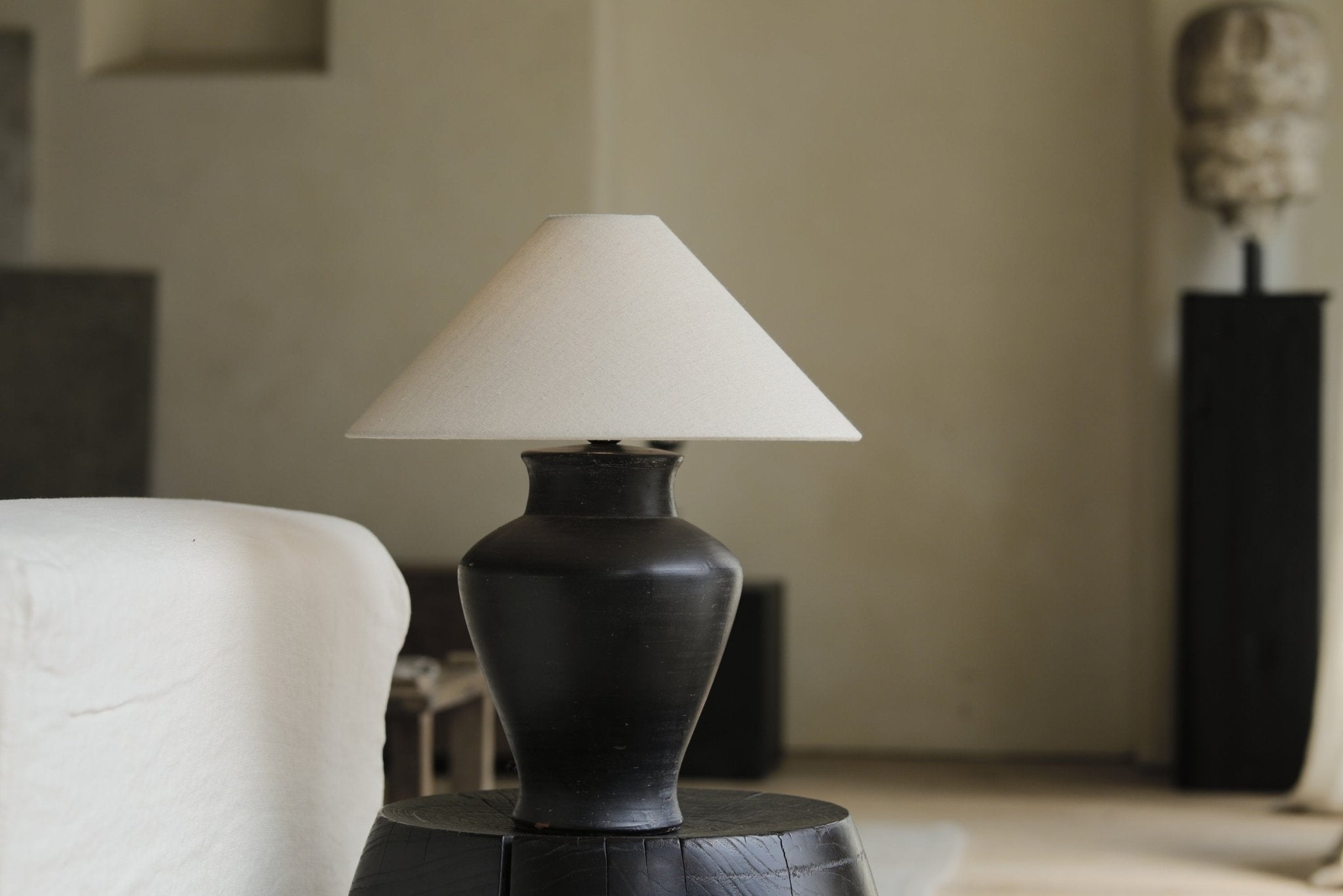 Short neck lamp with clay base and linen shade on wooden table