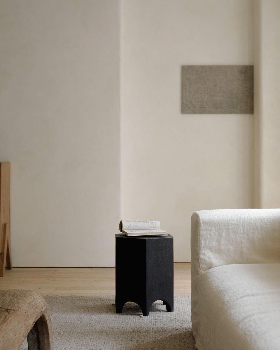 Black Hexagon Side Table next to cream sofa, a versatile accent piece in a modern living room. Geometric design.