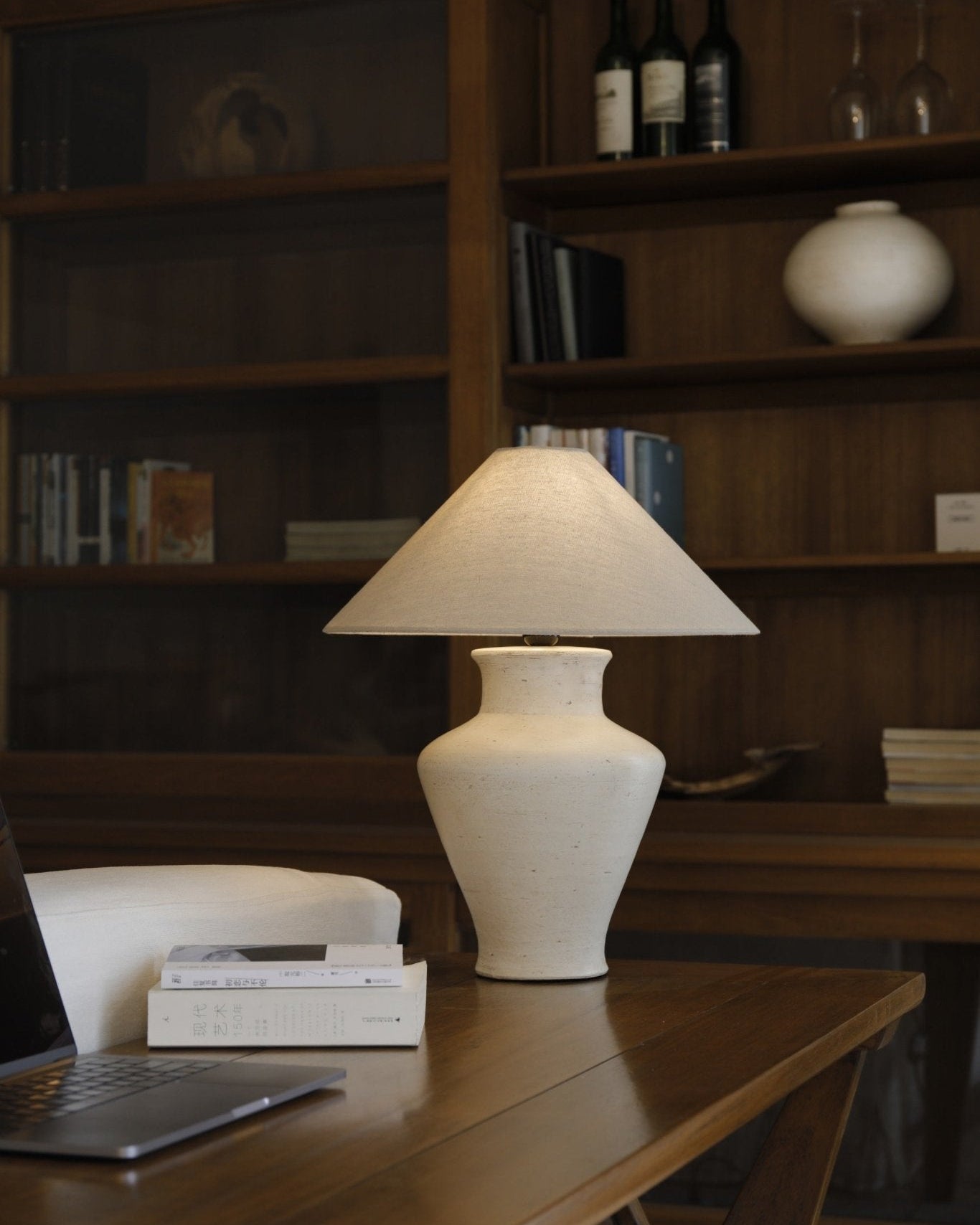Short neck lamp with clay base and linen shade on wooden table, modern design