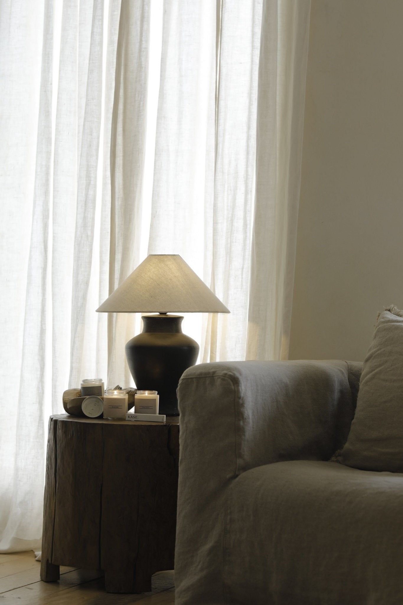 Short Neck Lamp with clay base, linen shade, and candles on wooden table, interior design