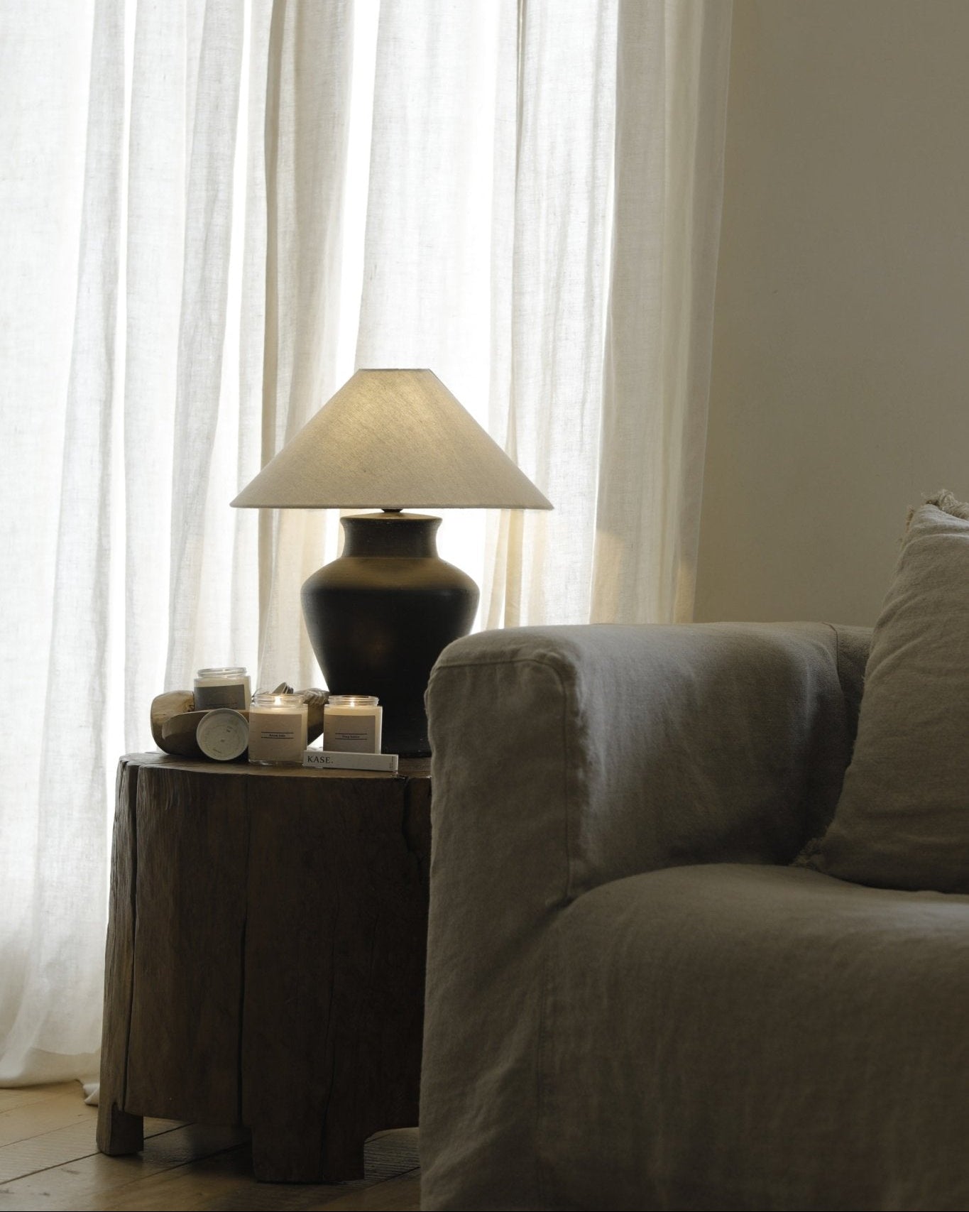 Short Neck Lamp with clay base, linen shade, and candles on wooden table, interior design