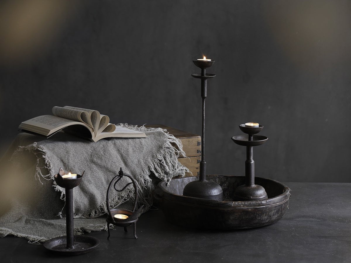 Rustic iron candle holder set with lit candles, book, and cozy home décor ambiance
