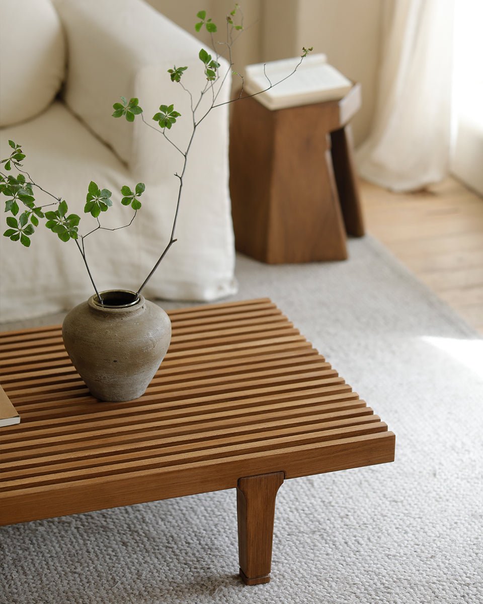 ZM Daybed Coffee Table in teak wood with slatted design, vase with green leaves, modern living room setting