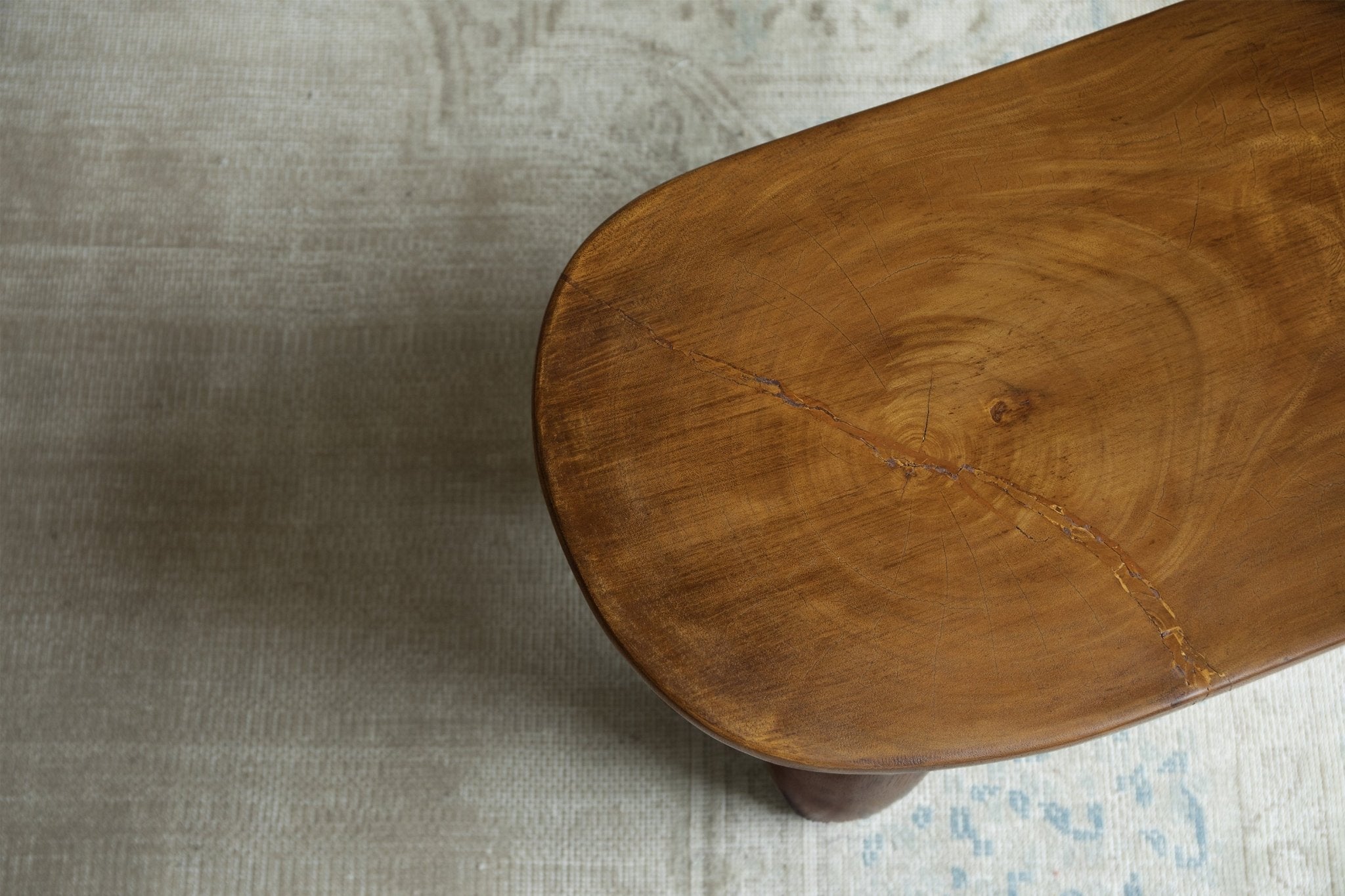 Close-up of a handcrafted milk stool made of Samanea saman wood, showcasing natural wood grain, perfect for a living room.