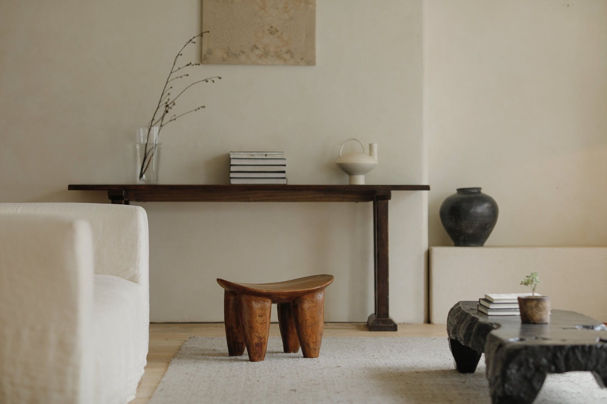 Samanea saman wood milk stool in a living room setting. Natural finish, minimalist decor.