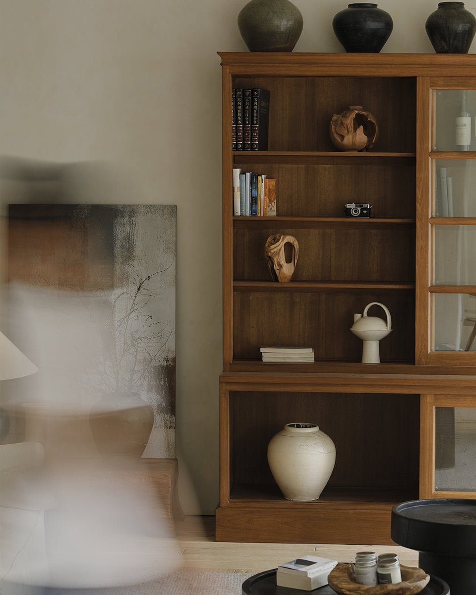 African teak glass bookcase showcasing books and decorative items