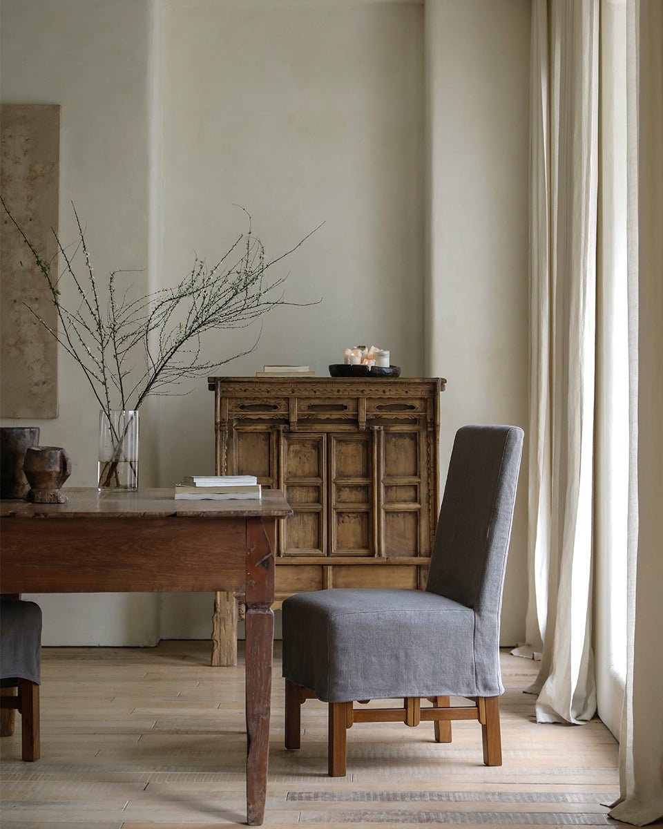 Feast Dining Chair with gray linen slipcover in a modern dining room, wooden frame, neutral tones.