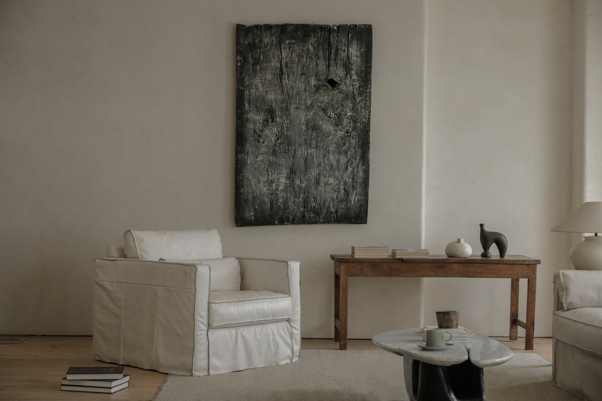 Cream skirt leather armchair in modern living room with wooden accents and artwork, highlighting the elegant skirt design.