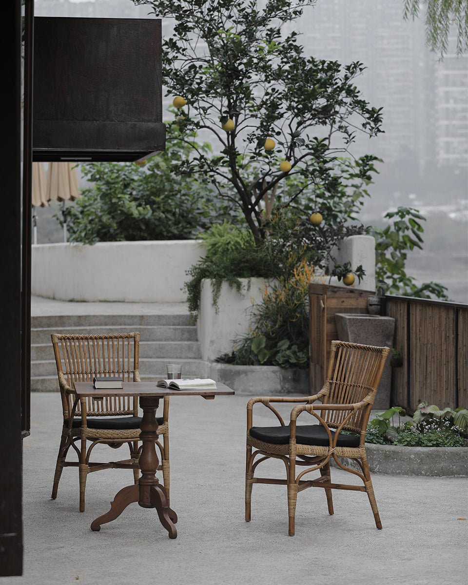 Axis Chair dining set with Indonesian rattan chairs, black cushions, and wooden table, outdoor setting.