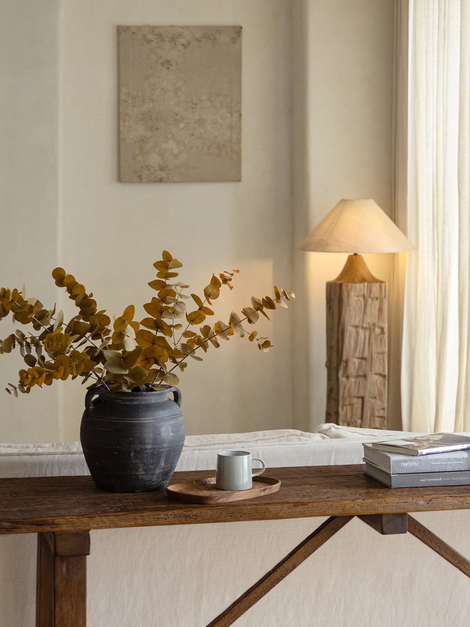 Vintage clay pot with eucalyptus branches, wooden table, home decor accent, neutral color palette.