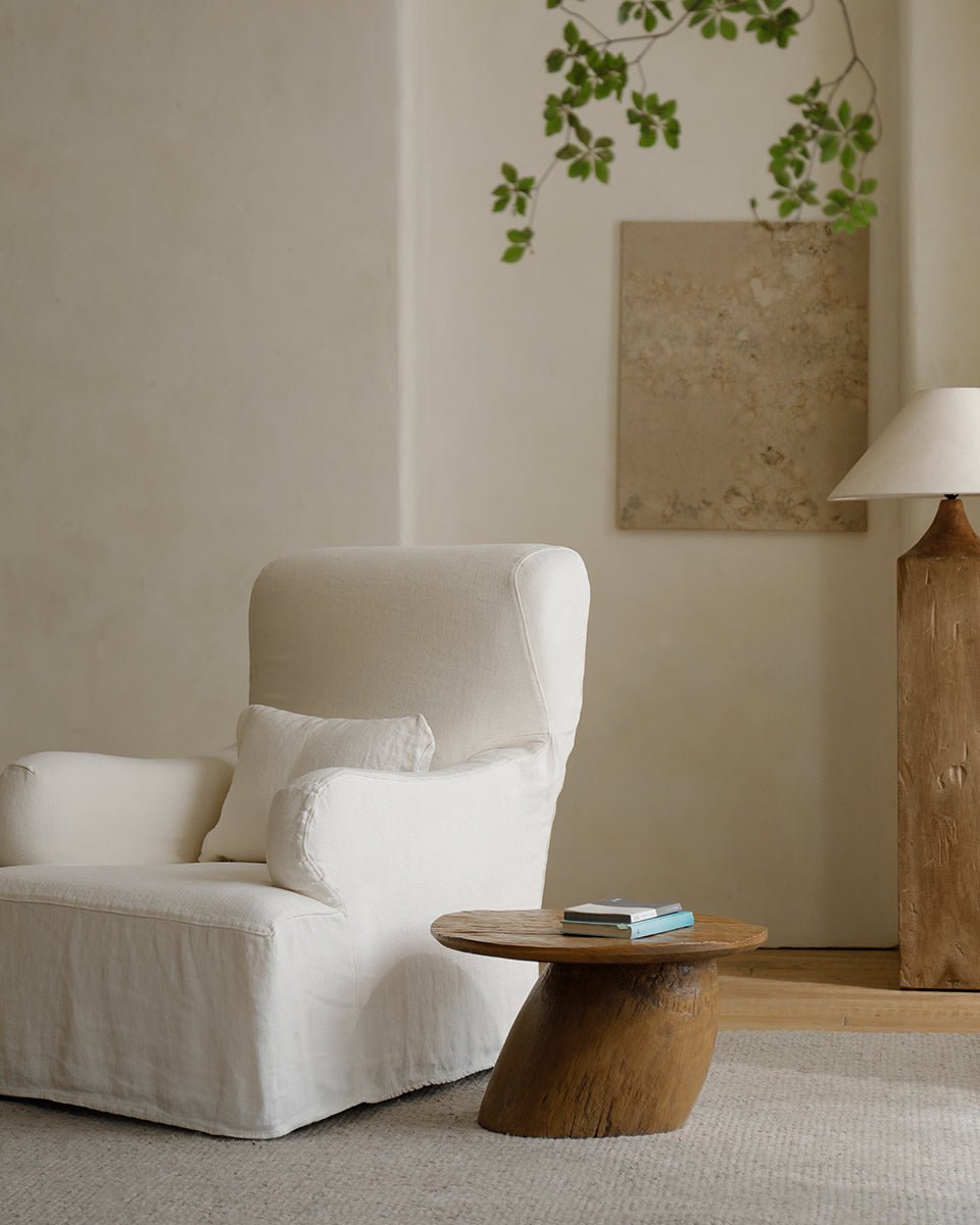 Alva Side Table in a cozy living room setting, featuring a distorted base and natural wood.