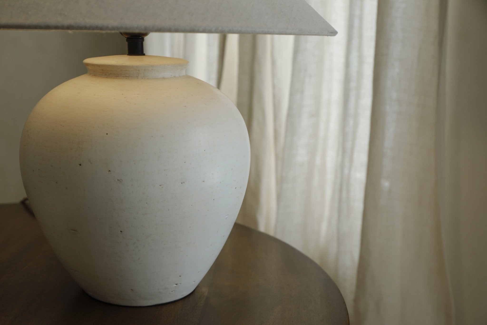 Off-white clay Egg Lamp with linen lampshade on a wooden table, modern interior decor, neutral tones