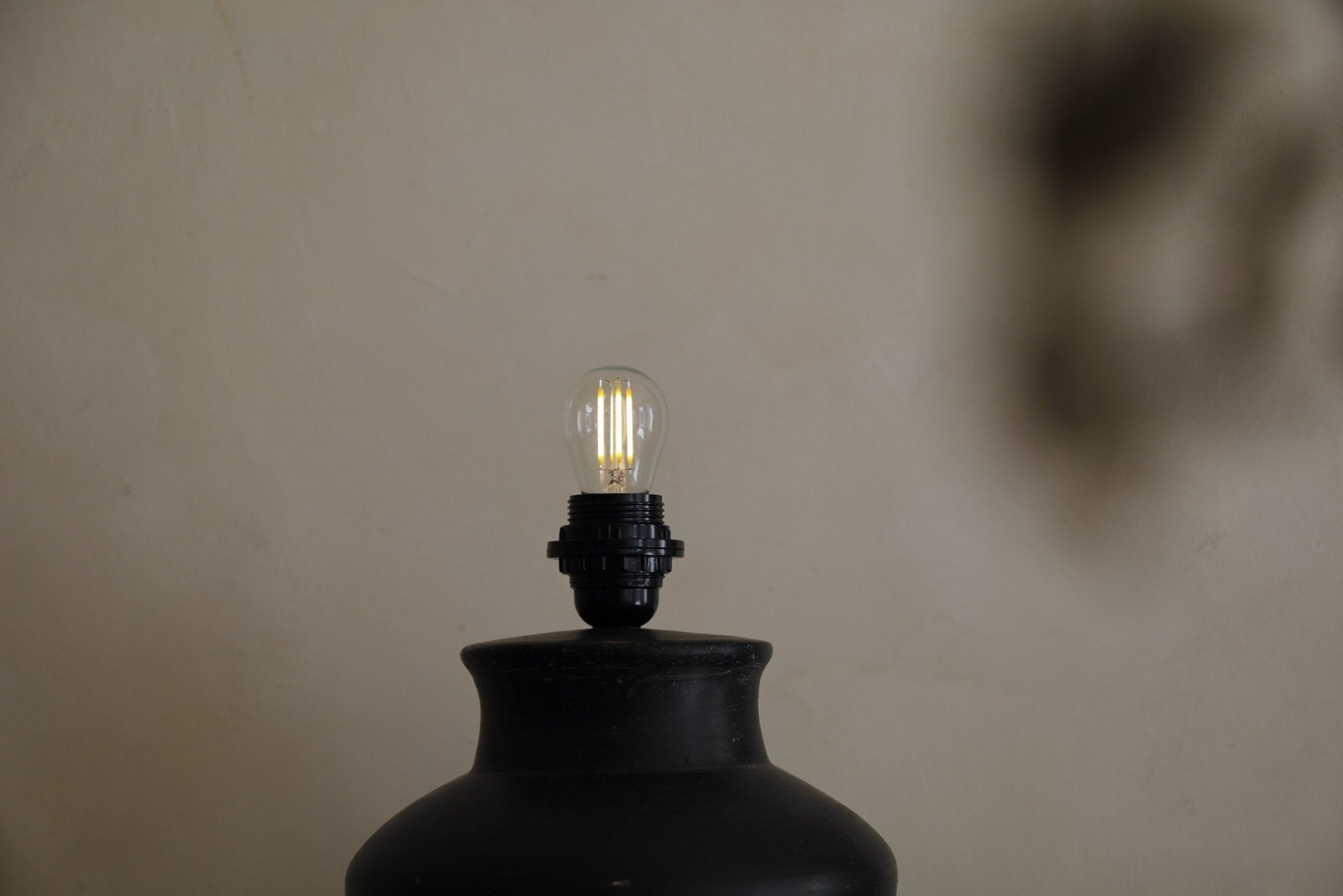 Black short neck lamp with illuminated bulb. Clay base Short Neck Lamp