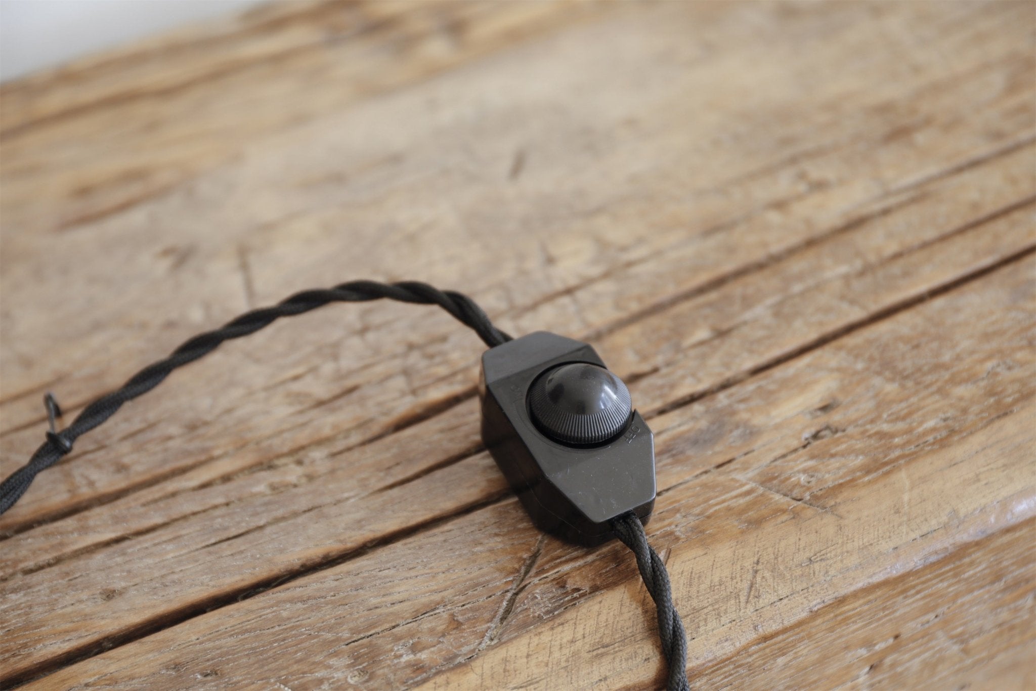 Black dimmer switch for short neck lamp, wooden table background, adjustable lighting.