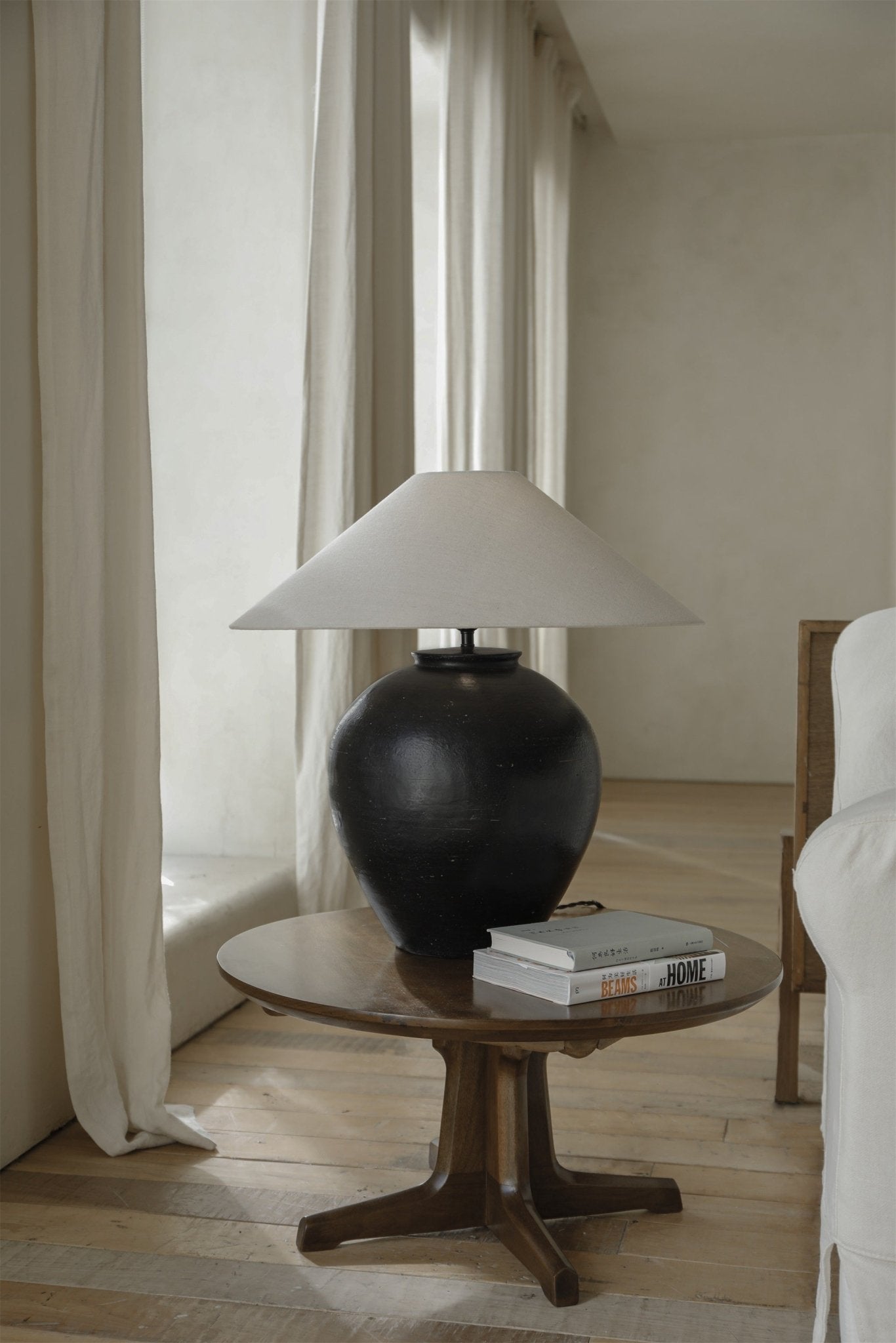 Modern black clay Egg Lamp with white lampshade on wooden table, BEAMS AT HOME books beside