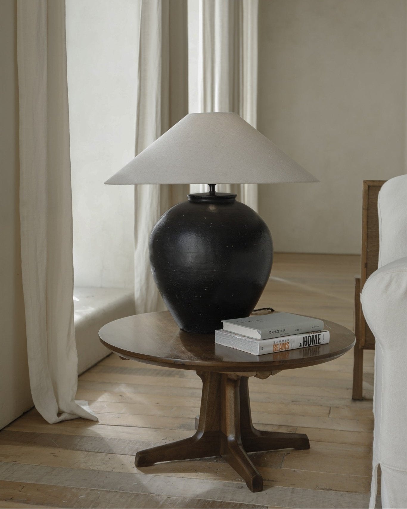 Modern black clay Egg Lamp with white lampshade on wooden table, BEAMS AT HOME books beside