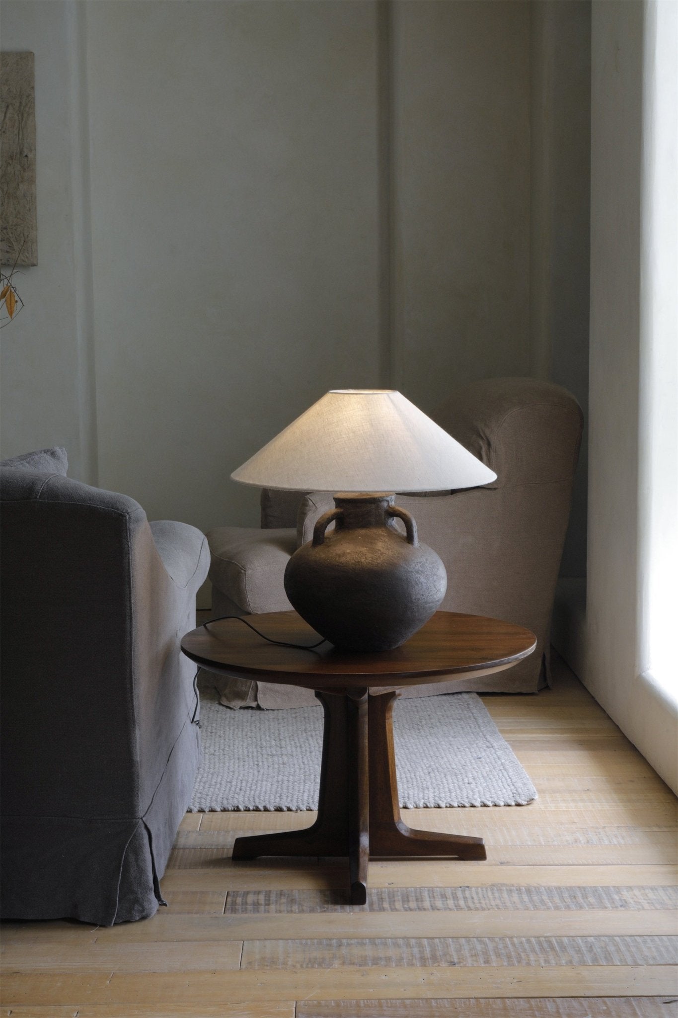 Ear Lamp with dark clay base and white shade on a wooden table, home decor.