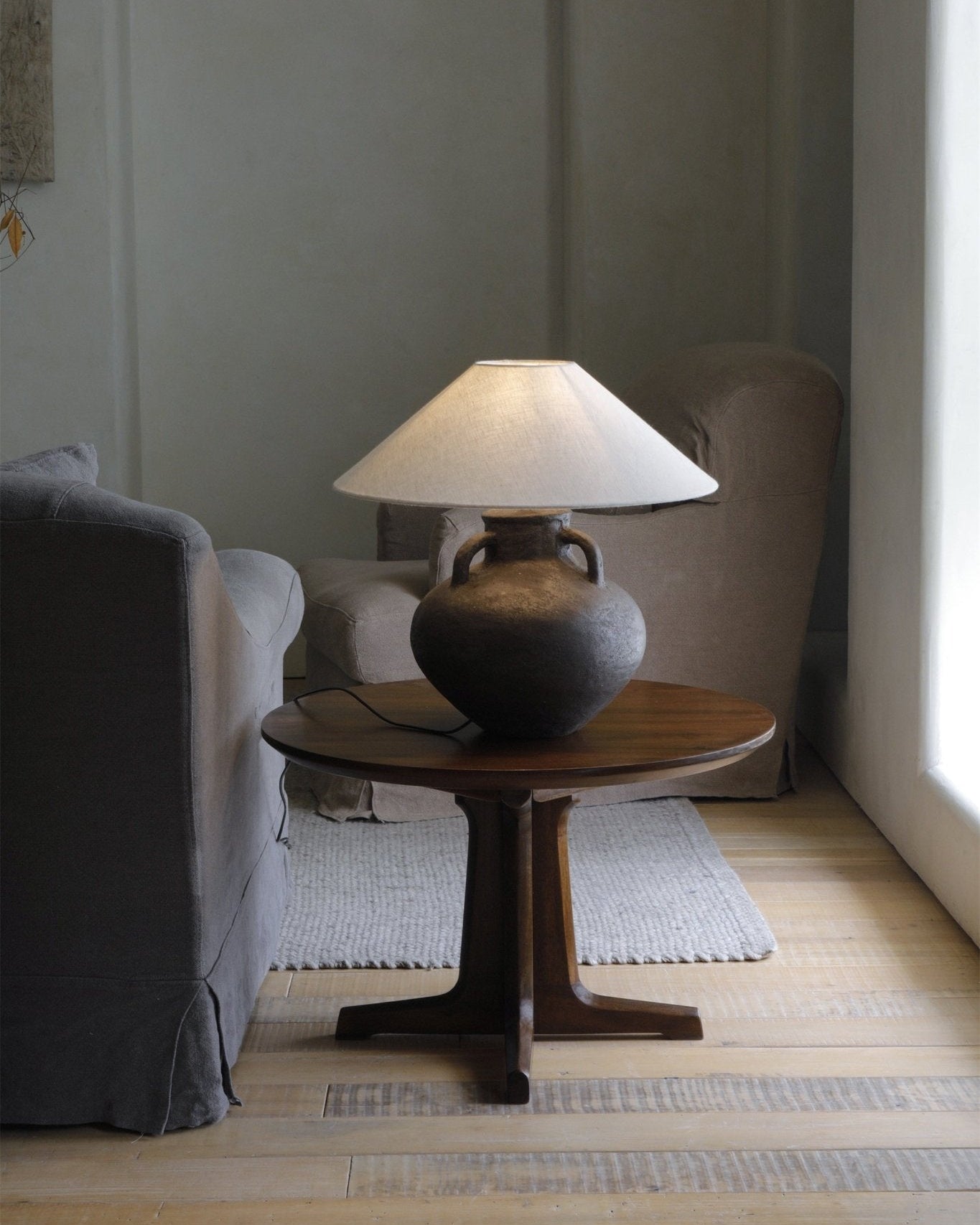 Ear Lamp with dark clay base and white shade on a wooden table, home decor.