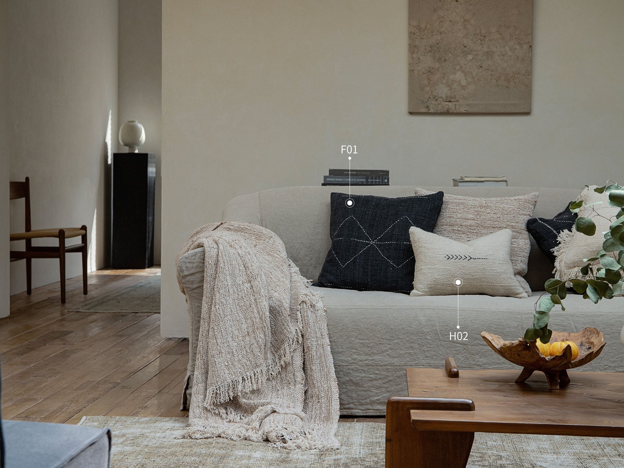 Cotton pillows on beige sofa, F01 and H02 product references, with stitched designs and a neutral color palette