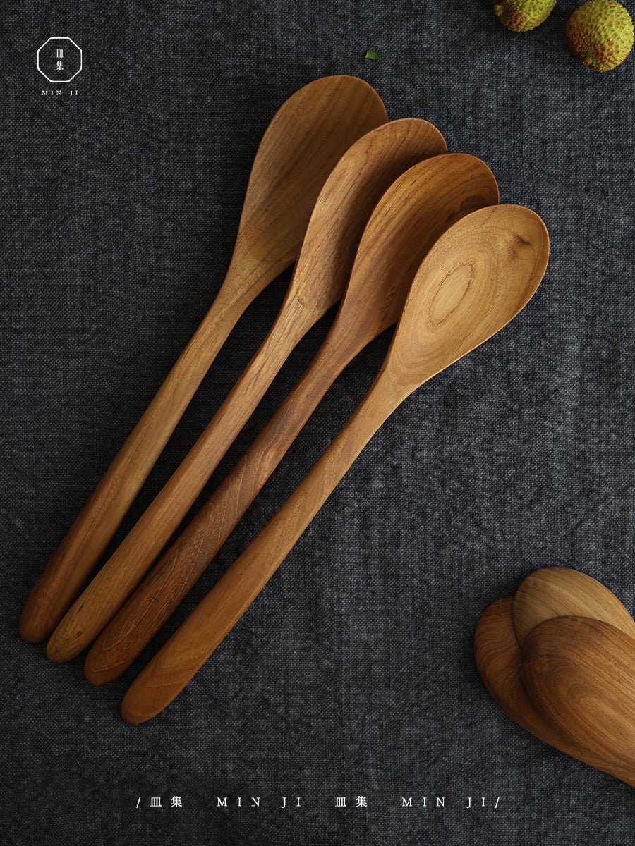 MIN JI wooden salad spoons on dark grey cloth. Natural wood grain and texture.