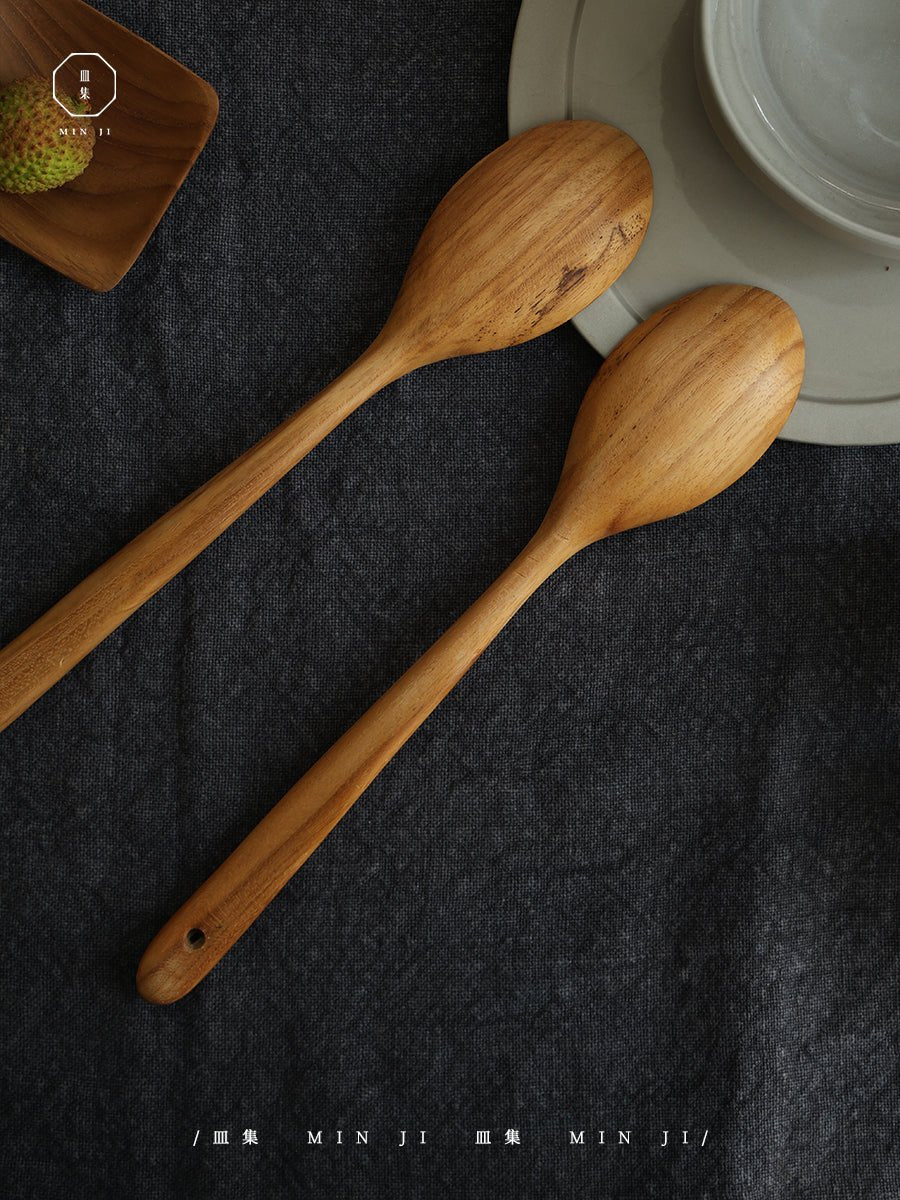 MIN JI Salad Spoons - Pair of wooden spoons with natural wood grain, on a dark grey background, perfect for salads.