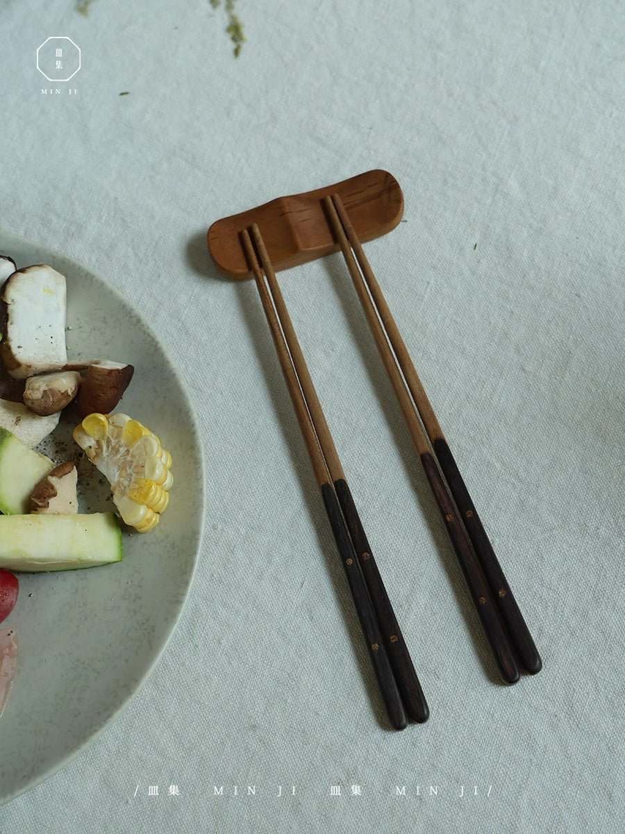 Two pairs of chopsticks with a wooden holder, MIN JI design, perfect for Asian cuisine.