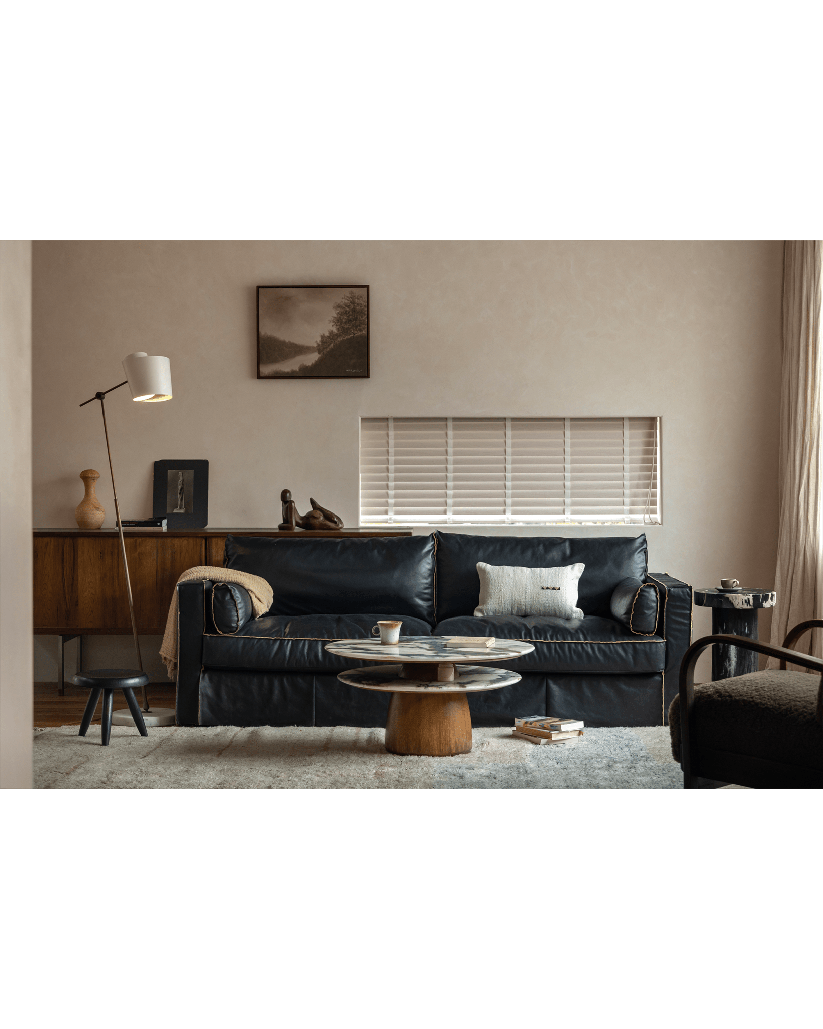Modern living room with a Dorothy Side Table with crystal stone top, black leather sofa, and round coffee table.