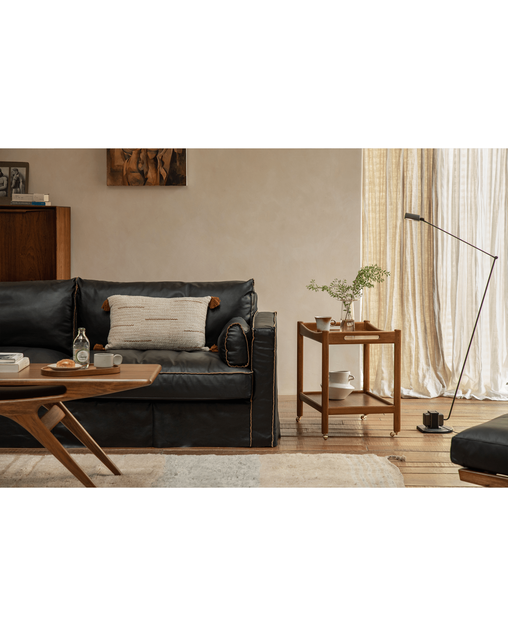 Brooklyn Bar Cart styled in living room with black leather sofa, wooden table, and brass casters