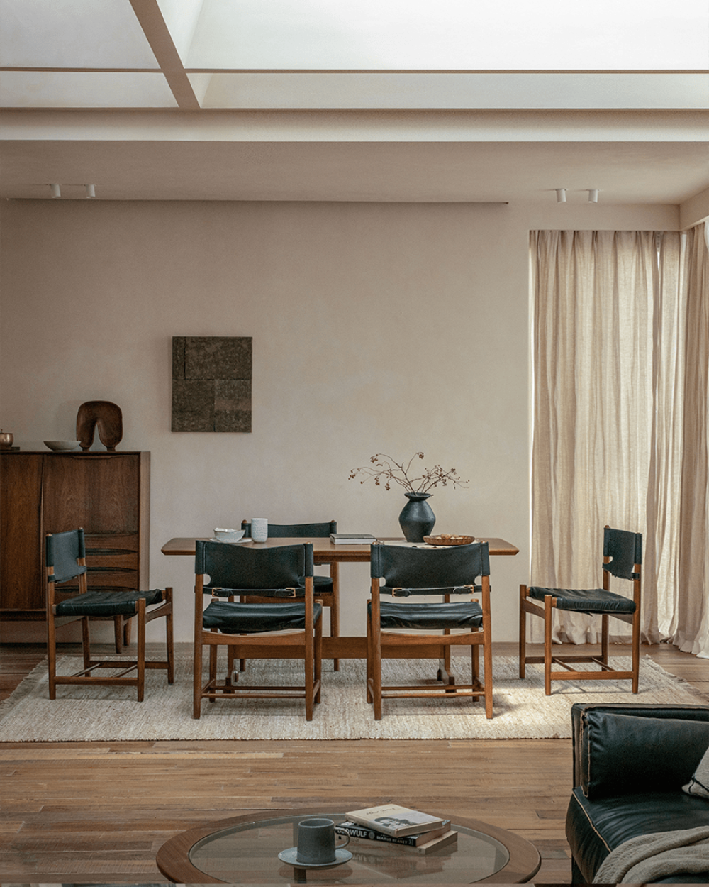 Spanish Dining Chair arrangement: Black leather and teak wood chairs around a dining table, durable design.